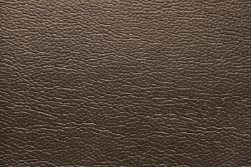 Glossy structure of genuine leather, natural skin surface with embossing pattern. Artifical brown colored leatharette close up, macro texture. Background, wallpaper, backdrop.