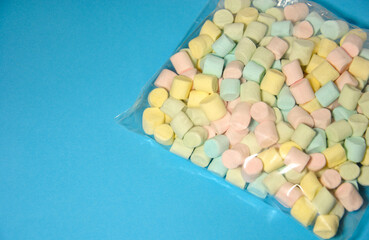 colored marshmallows in packaging on a blue background