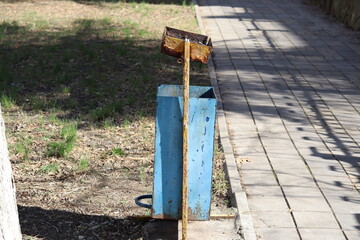 A trash can, metal, rusty, old, on the street. Painted blue.