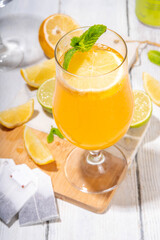Trendy Tea Inspired cocktail set from green, oolong, black, chai and other tea blends. Sparkling tea soda, cold summer drinks with syrup, lemon, lime and mint, on sun lighted white wooden background