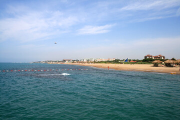 Sandy beach with blue sea and resort hotels in the background.