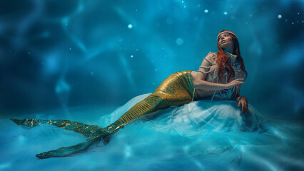 Beautiful redhaired woman, mermaid resting on soft waves, gazing into the distance with mystery and...