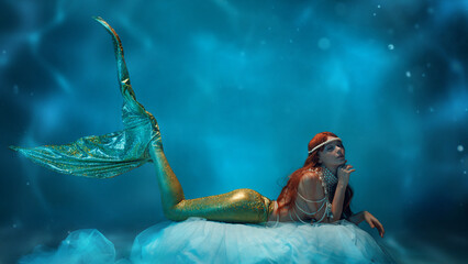 Elegant redhaired woman, mermaid resting on flowing transparent fabric, gazing dreamily into...