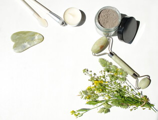 Skin care products and devices, cosmetic clay, mask, bouquet of yellow wild flowers on a white...