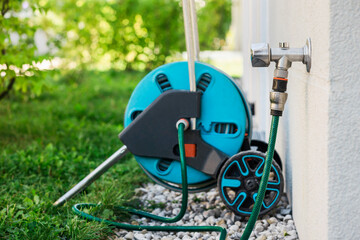 Hose Reel Cart Сonnected with Tap Outside of House Wall. Modern Retractable Hose for Watering...