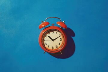 Red alarm clock on a vibrant blue background
