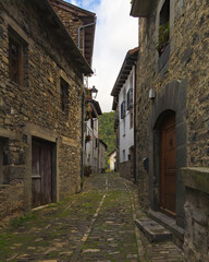 Calle empedrada con casas de piedra y balcones floridos en Isaba, Navarra, España.