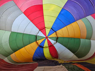 Looking into the center of a colorful hot air balloon as it is lying on the ground being inflated with air during launch preparations.