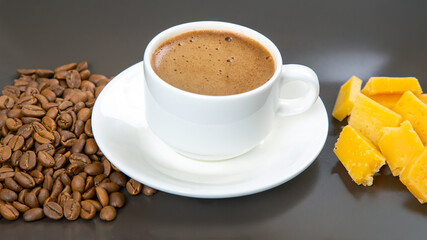 Fototapeta premium A minimalist scene featuring espresso in a white cup, cheese sticks, and roasted coffee beans on a dark table, ideal for food photography