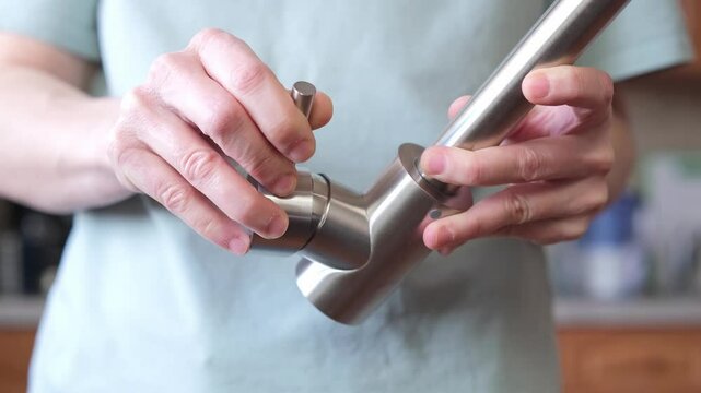 Close-up of hands adjusting a stainless kitchen faucet. Checking the serviceability of a single-valve kitchen faucet.