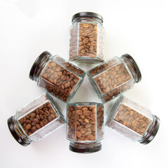 six glass jars with black lids filled with roasted coffee beans on a white background