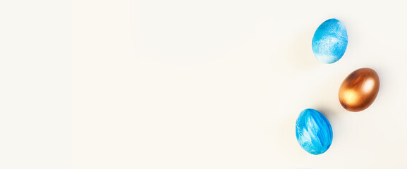 Frame of Easter colorful blue and golden color eggs on pastel pink background. Stylish trendy gold chocolate egg set isolated. Flat lay, top view, place for text. Happy egg hunt for kids concept