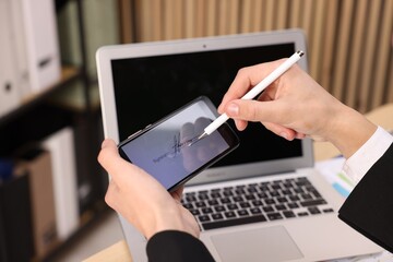 Electronic signature. Man using stylus and smartphone at table indoors, closeup