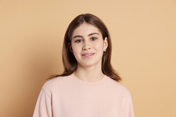 Portrait of beautiful teenage girl on beige background