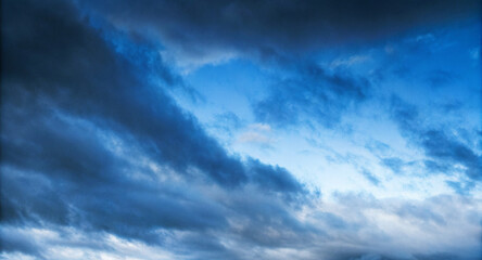 Obraz premium dramatic sky filled with a mix of dark and light shades of blue, swirling clouds, copy space for text