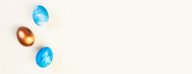 Frame of Easter colorful blue and golden color eggs on pastel pink background. Stylish trendy gold chocolate egg set isolated. Flat lay, top view, place for text. Happy egg hunt for kids concept