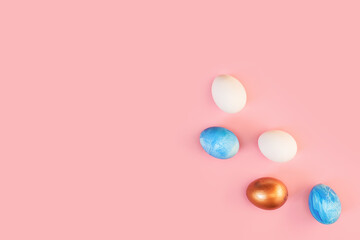 Frame of Easter colorful blue golden and white color eggs on pastel pink background. Stylish trendy gold chocolate egg set isolated. Flat lay, top view, place for text. Happy egg hunt for kids concept