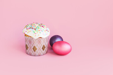 Traditional russian Easter ortodox cake with daffodil flower and colorful eggs on light pink background. Kulic, Kulich, Paska homemade bread with glaze. Spring christian holiday. Festive celebration