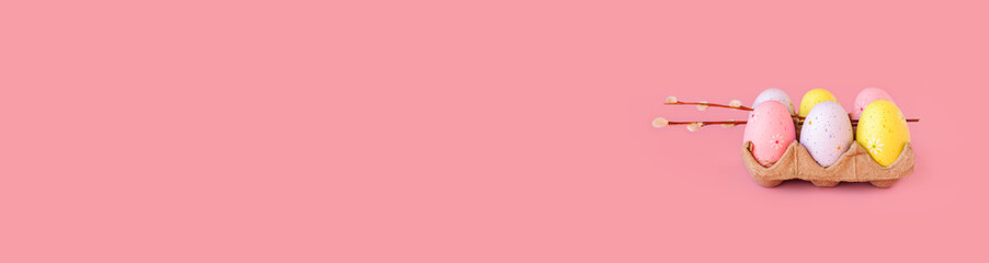 Eco basket with colorful easter eggs and willow branch on pastel light pink background. minimalistic decoration, minimal composition. Front view, place for text, banner