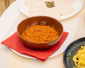 Terracotta bowl with beans in tomato sauce served in restaurant setting