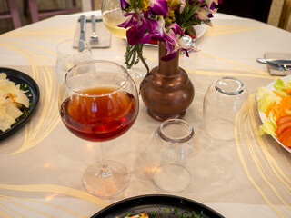 Glass of red wine on restaurant table with appetizers and flowers centerpiece