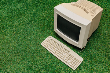 Vintage PC on green grass, top view. Monitor and keyboard as in 90s
