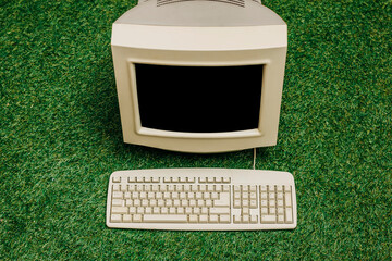 Vintage PC on green grass, top view. Monitor and keyboard as in 90s