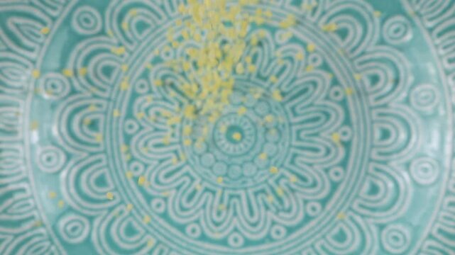 Couscous grits are poured into a blue ceramic bowl. Top view. Slow motion.