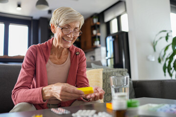 Senior woman carefully reading a prescription bottle while sitting at home. She is managing her medications responsibly, ensuring proper healthcare and treatment for a healthy lifestyle.