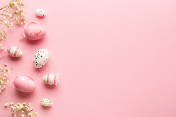 Easter eggs on pink background. Colored eggs, flowers, holiday decorations. Flat lay with copy space.