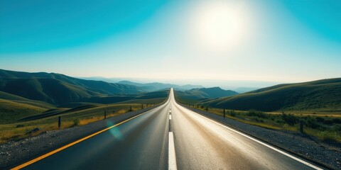 Asphalt highway stretching towards distant sunlit hills under a vibrant blue sky
