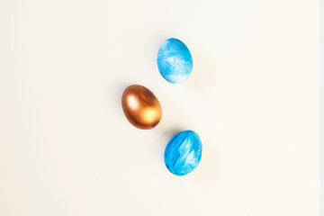 Frame of Easter colorful blue and golden color eggs on pastel pink background. Stylish trendy gold chocolate egg set isolated. Flat lay, top view, place for text. Happy egg hunt for kids concept