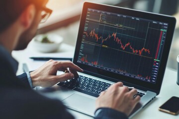 Young professional analyzing stock market trends on a laptop in a modern office setting, showcasing focus and determination