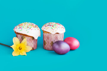 Traditional russian Easter ortodox cake with daffodil flower and colorful eggs on light pink background. Kulic, Kulich, Paska homemade bread with glaze. Spring christian holiday. Festive celebration