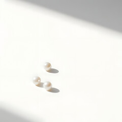 A soft-focus shot of a few pearls scattered across a minimalist white background, with natural light gently highlighting their round shapes
