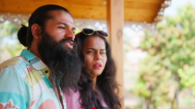 Bearded guy points in resort showing lady around