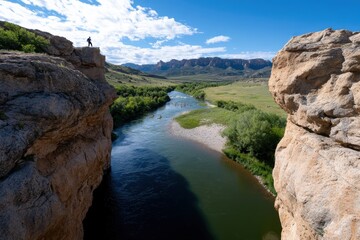 This scenic image showcases an adventurer watching a tranquil river below, bordered by lush greenery and magnificent cliffs, evoking a sense of freedom and adventure.