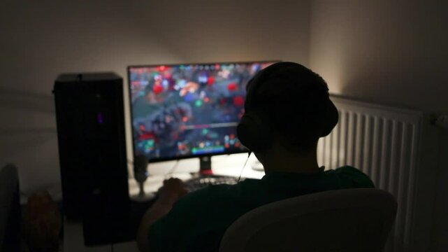 Selective focus on Caucasian gamer using gaming pc professional setup while having fun playing online games at home. Man enjoying relaxing free time streaming multiplayer competition.