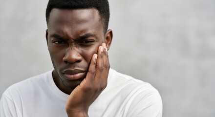 African male adult with toothache holding jaw in painful expression