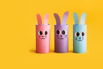 Holiday easy DIY craft idea for kids. Toilet paper roll tube toy's cute rabbit's on yellow background. Creative Easter or Christmas decoration eco-friendly, reuse, recycle handmade minimal concept