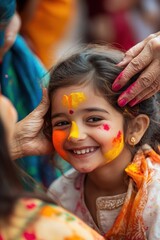 Obraz premium A young girl giggling as her grandmother applies Holi color to her cheeks, a beautiful moment of tradition