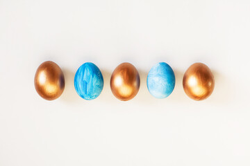Set of Easter blue and golden color eggs isolated on white background. Stylish trendy frame composition with gold chocolate egg. Flat lay, top view, place for text. Happy egg hunt for kids concept