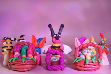 Toy little gnomes, bees and Easter baskets on a pink background.