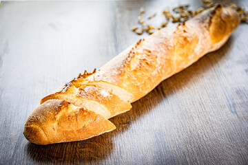 still life with French fresh bread baguettes with poolish on a wooden cutting board and wheat, shallow dof