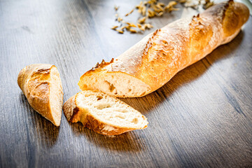 still life with French fresh bread baguettes with poolish on a wooden cutting board and wheat,...