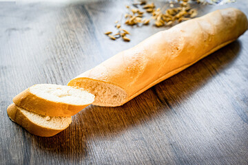 still life with French fresh bread baguettes with poolish on a wooden cutting board and wheat,...