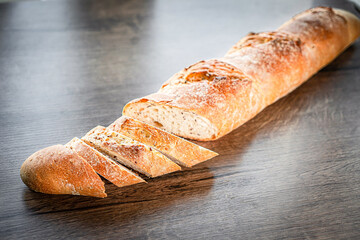 still life with French fresh bread baguettes with poolish on a wooden cutting board and wheat,...