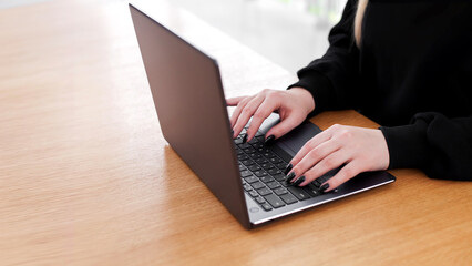 Young white caucasian woman working on computer on wooden table in home office. close up female businesswoman hands typing text on keyboard, surfing internet on modern laptop. mock up, top front view
