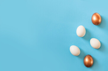 Set of Easter natural white and golden color eggs isolated on blue background. Stylish trendy frame composition with gold egg. Flat lay, top view, place for text. Happy egg hunt for kids concept