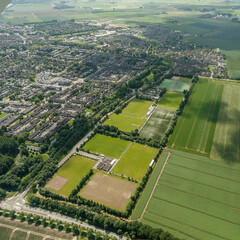 Aerial view of Zevenbergen showcasing green fields, urban development, and farmland during a sunny day
